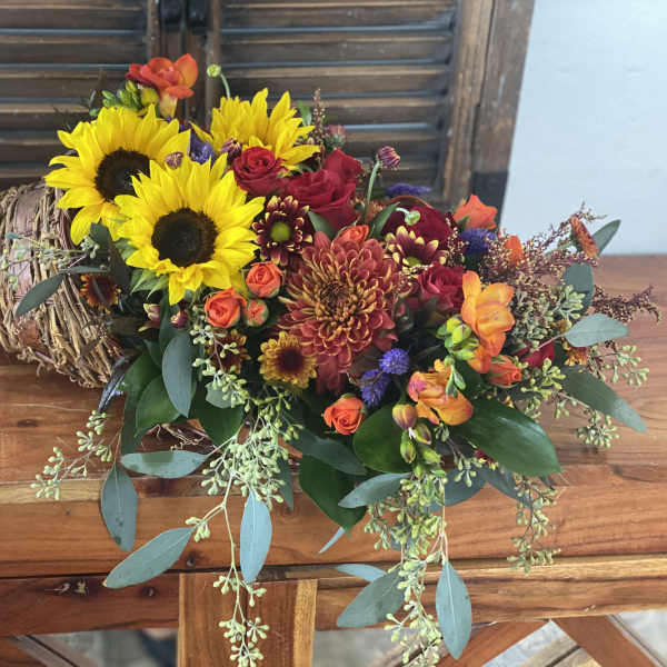 Mixed bouquet with sunflowers, roses, and chrysanthemums in a woven wrap