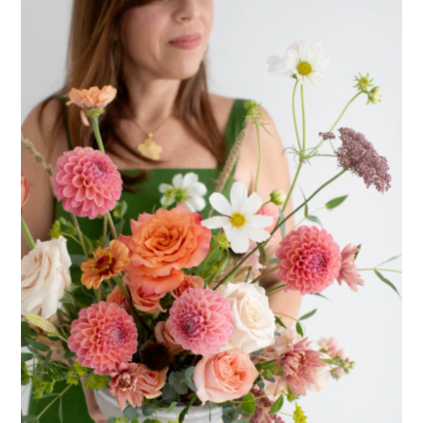 Woman holding a mixed bouquet of pink, peach, and white flowers