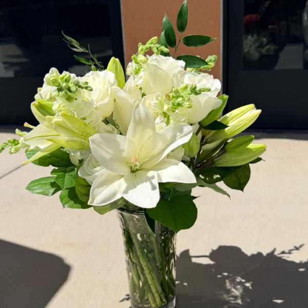 White lilies and roses arranged in a clear glass vase