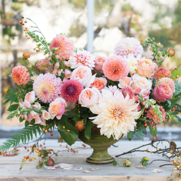 Peach and pink floral arrangement in a green pedestal vase