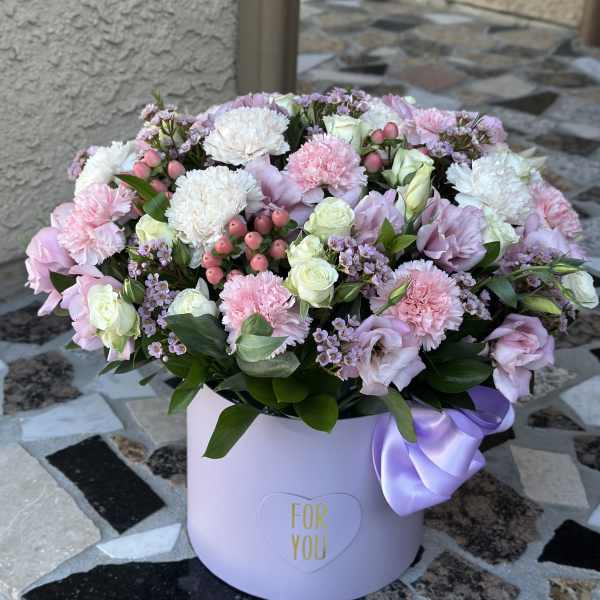 Pastel pink and white flower arrangement in a lavender hat box with a ribbon
