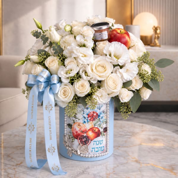 White rose arrangement in a blue decorated box with an apple and ribbon