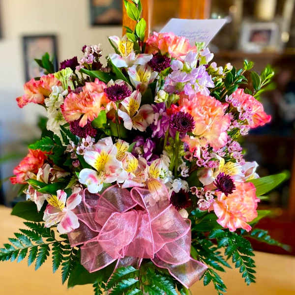 Mixed pink and white bouquet in a glass vase with a pink ribbon