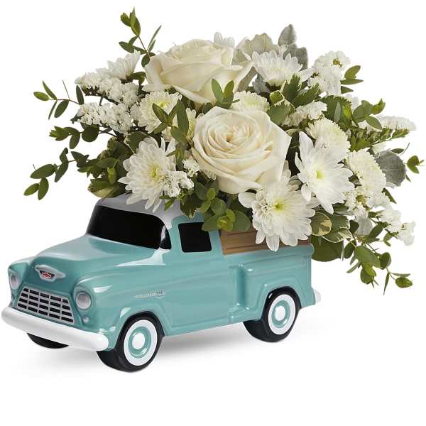 White roses and daisies arranged in a turquoise truck planter