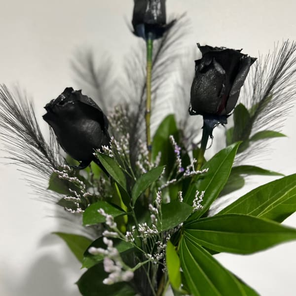 Black roses with green foliage and feathery accents