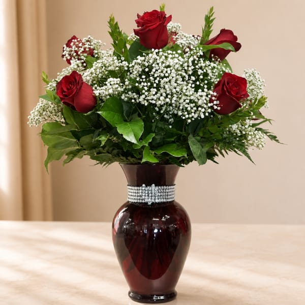 Red roses and white baby's breath in a dark glass vase