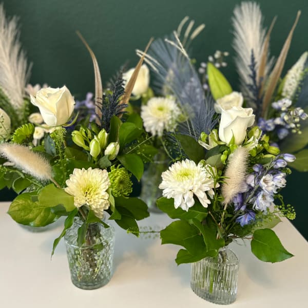Two floral arrangements in glass vases with white roses and chrysanthemums