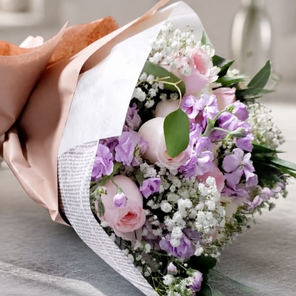 Bouquet of pink and lavender flowers wrapped in peach and white paper