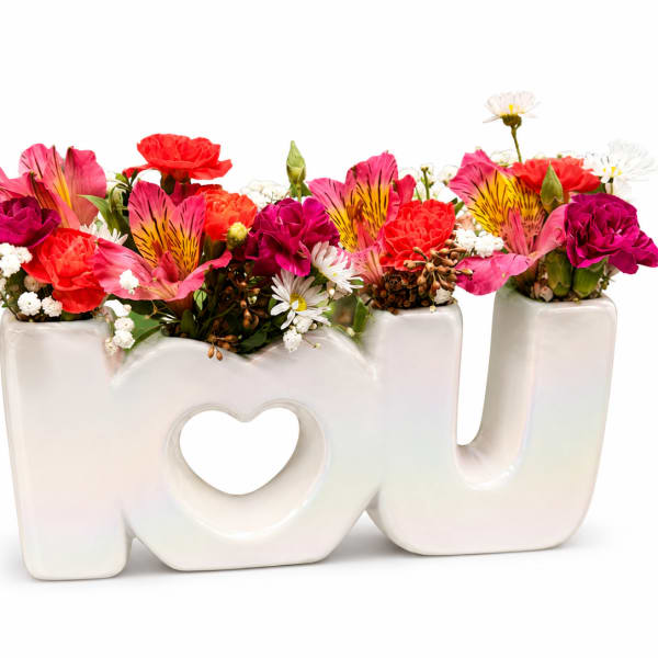 Colorful mixed flowers arranged in a white "MOM" vase with a heart cutout