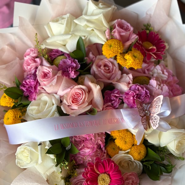 Pink and white rose bouquet with yellow pompom flowers and a ribbon
