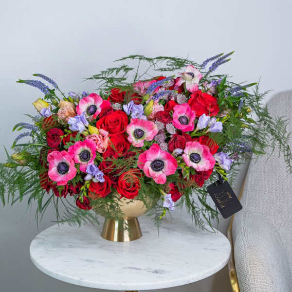 Large bouquet of red and pink flowers in a gold vase