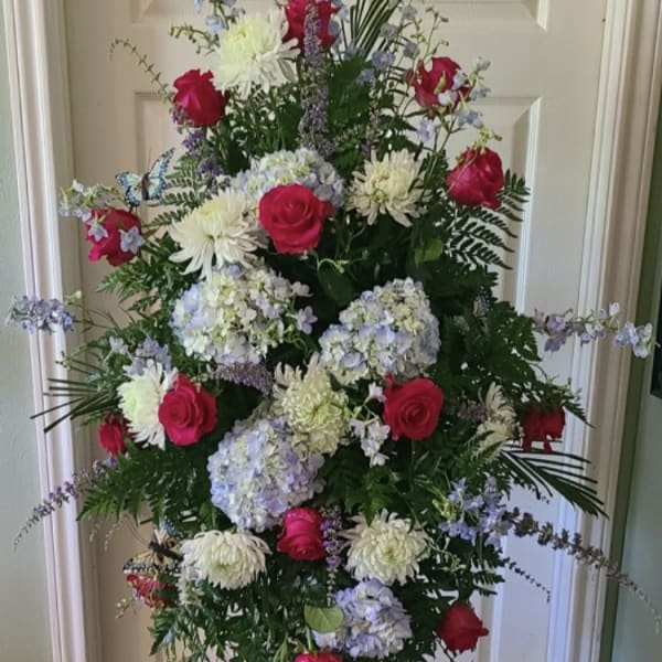 Tall floral standing spray with pink roses, white blooms, and blue hydrangeas