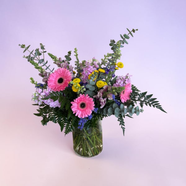 Pink gerbera daisies and mixed flowers in a glass vase