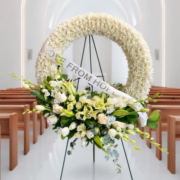 White floral wreath and bouquet on an easel with a "LOVE FROM HOPE" ribbon