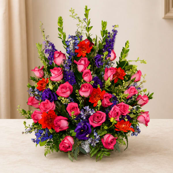 Bright mixed bouquet of pink roses, purple blooms, and orange flowers in a vase