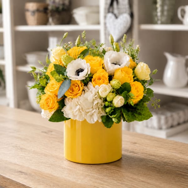 Yellow and white flower arrangement in a yellow vase