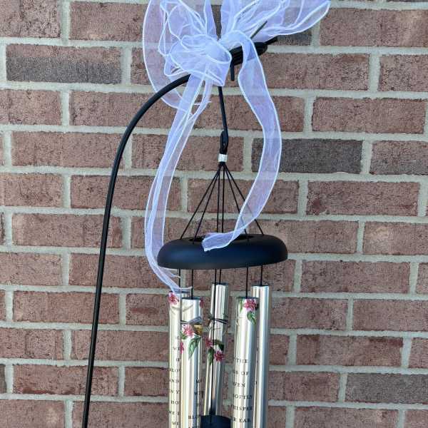Black wind chime with silver tubes and a white ribbon bow