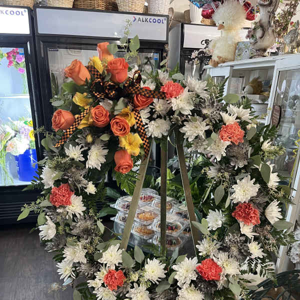 Large floral wreath on an easel with orange roses and white daisies