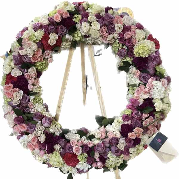 Large circular floral wreath on a stand with pink, purple, and white roses