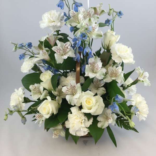White roses, alstroemeria, and blue flowers in a basket arrangement