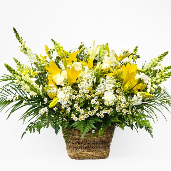Yellow and white floral arrangement in a woven basket