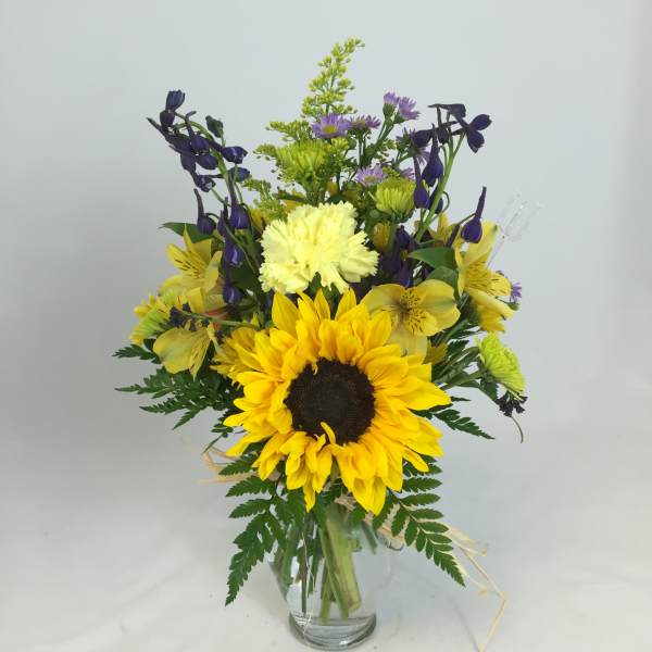 Sunflower bouquet with purple and yellow flowers in a glass vase