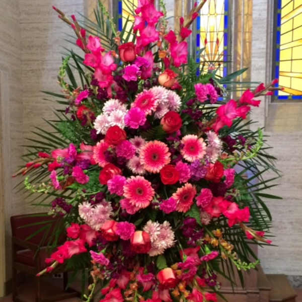 Tall standing spray of pink and red flowers on an easel