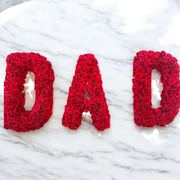 Red rose letters spelling "DAD" on a marble surface