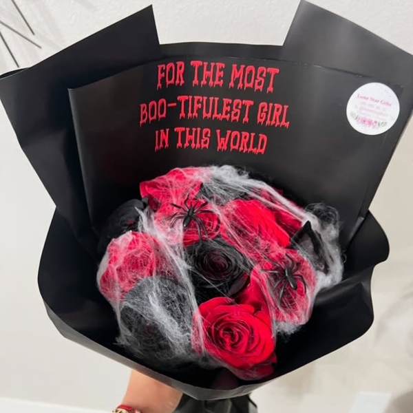 Black-wrapped bouquet of red roses with faux spiderwebs and plastic spiders