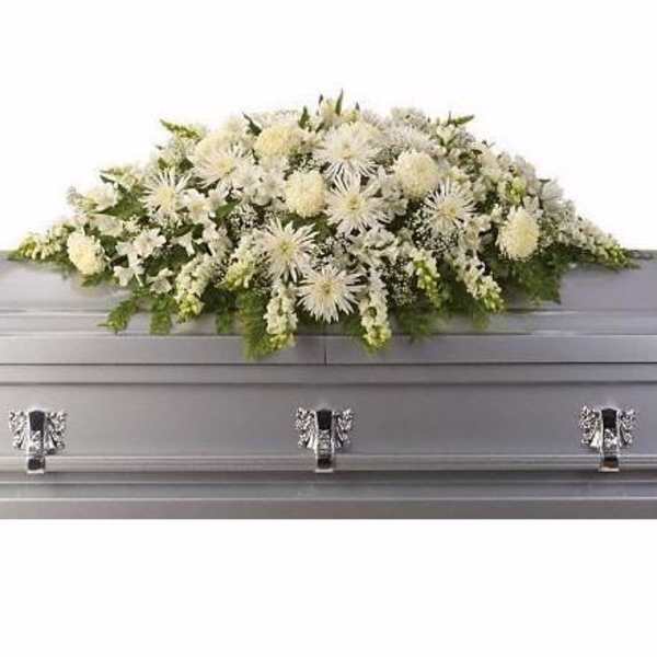 White floral casket spray with green accents on a gray casket