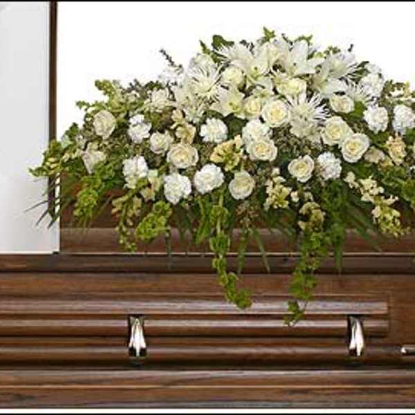 White floral spray arranged on top of a wooden casket