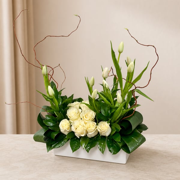 White roses and tulips arranged in a white rectangular vase
