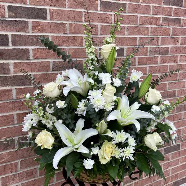 White lilies and roses in a basket arrangement with white daisies