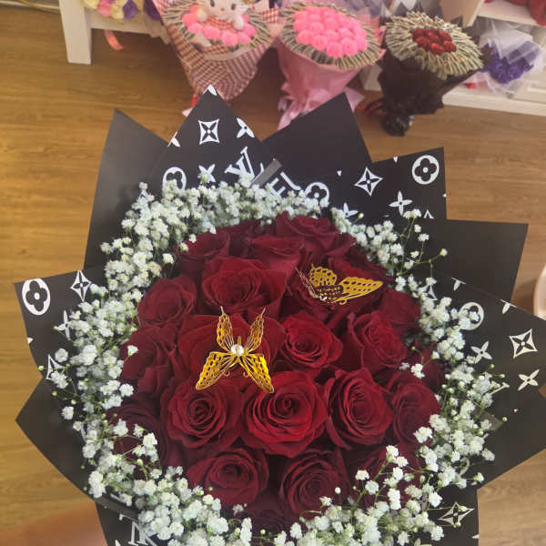 Bouquet of red roses with white baby's breath in black patterned wrap