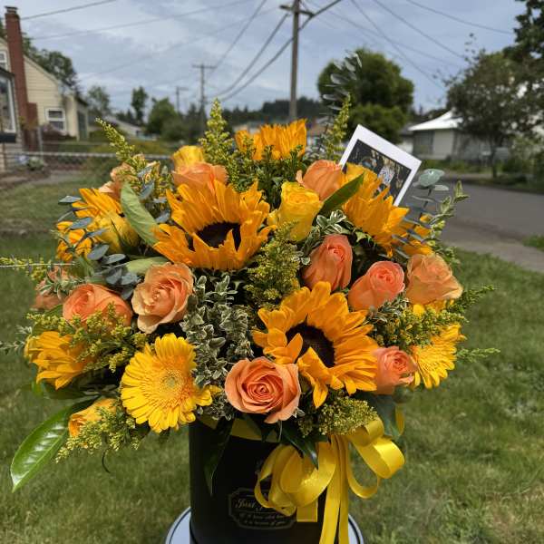 Bouquet of sunflowers and peach roses in a black hatbox with yellow ribbon
