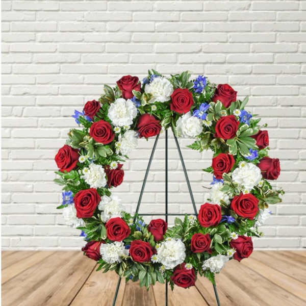 Circular wreath of red and white flowers on a black stand