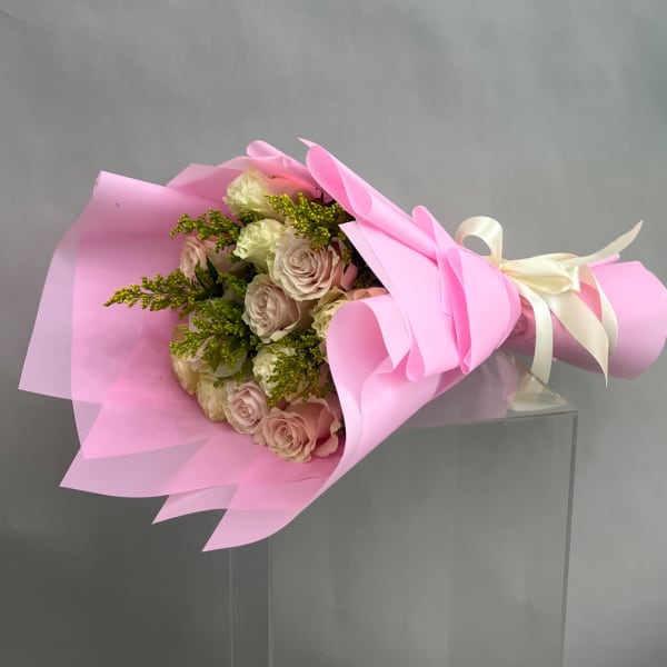 Pink and cream rose bouquet wrapped in pink paper with a ribbon
