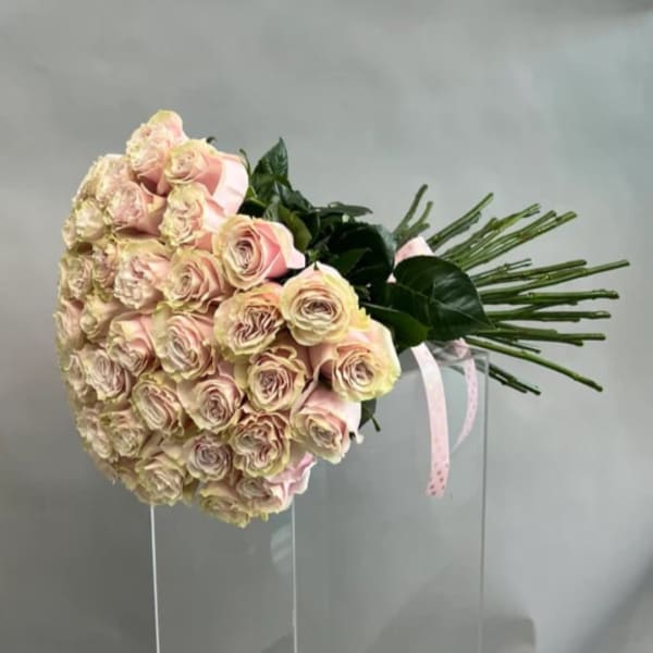 Large bouquet of pale pink roses with ribbon on a clear stand