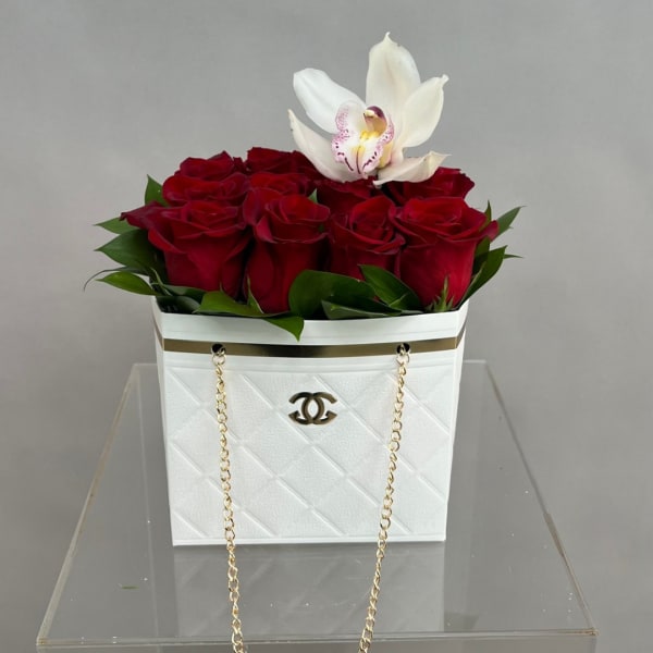 Red roses with a white orchid in a white handbag-style container