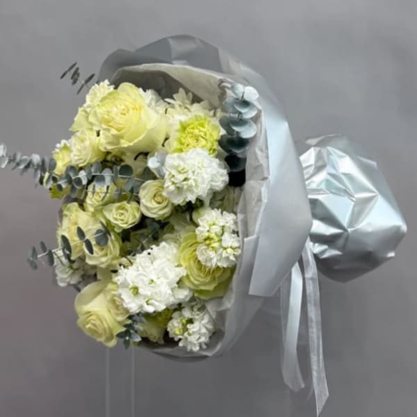 Bouquet of pale yellow and white flowers wrapped in silver paper