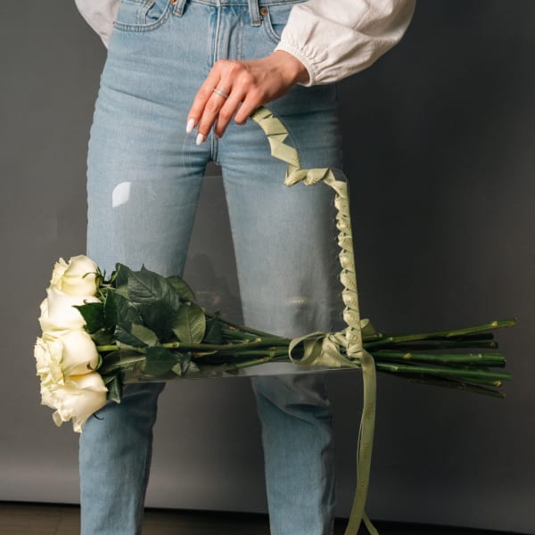 Person holding a bouquet of white roses with a ribbon