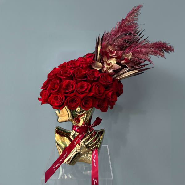 Red rose arrangement in a gold bust vase with a red ribbon