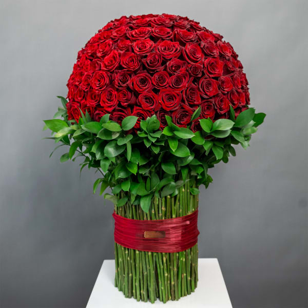 Large dome of red roses with green foliage and wrapped stems