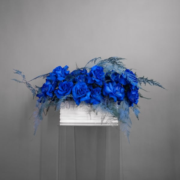Blue rose arrangement in a white rectangular container