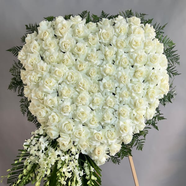 Heart-shaped arrangement of white roses with trailing white orchids