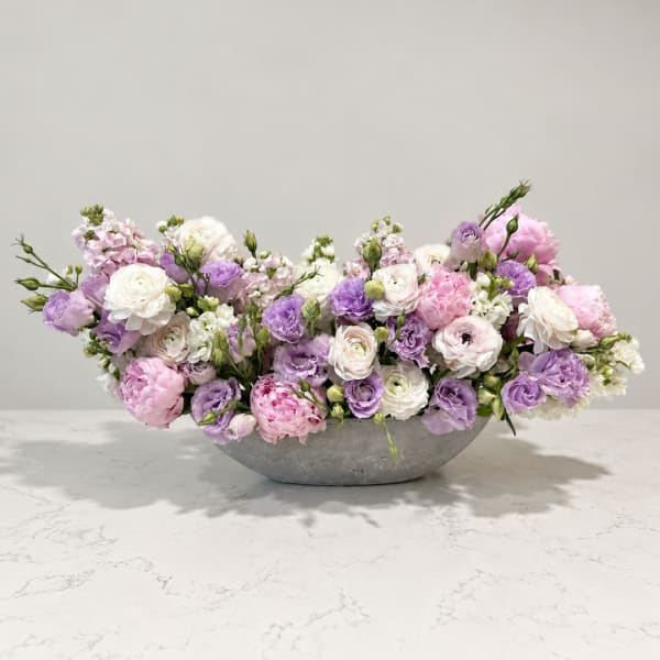 Low floral arrangement of pink, purple, and white blooms in a gray bowl vase