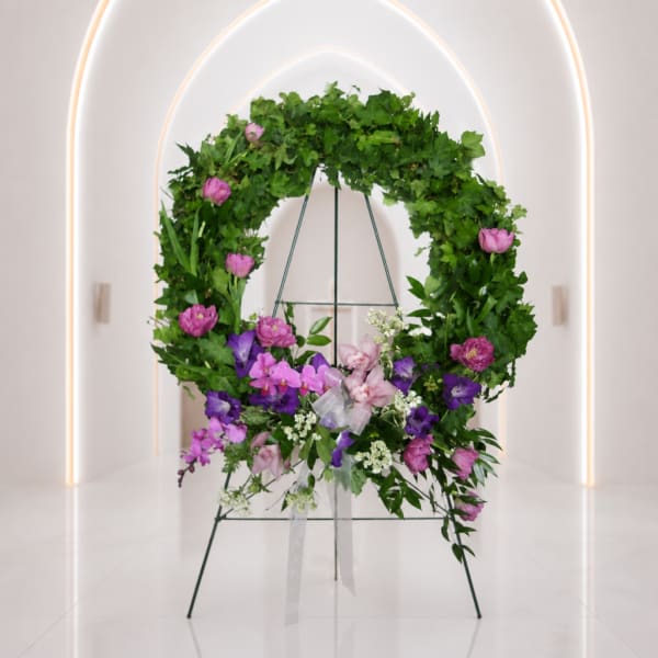 Circular floral wreath on a stand with pink and purple flowers