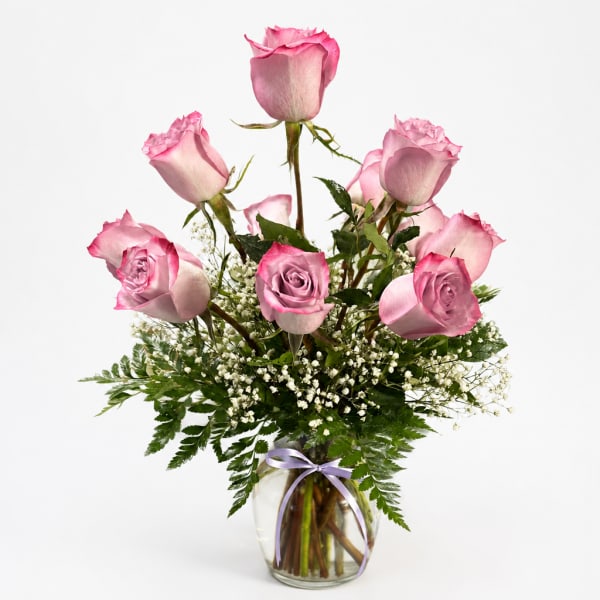 Pink roses arranged in a clear glass vase with baby's breath