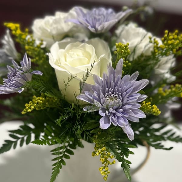 White roses and lavender daisies in a white vase