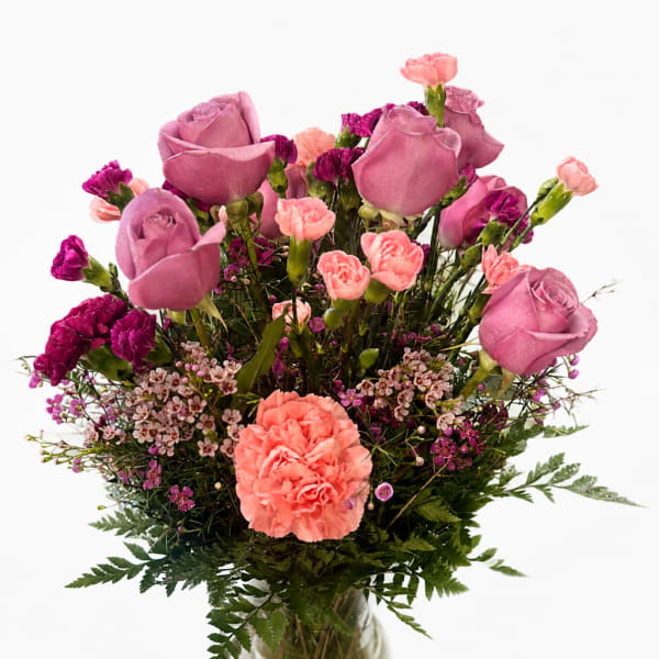 Pink roses and carnations arranged in a clear glass vase